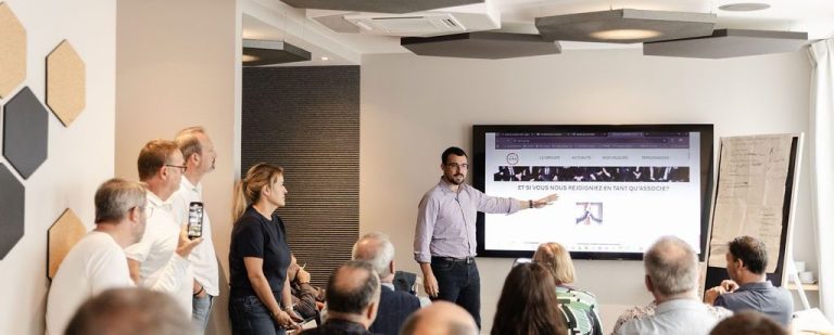 Un homme présente des informations à un groupe lors d'une réunion dans un bureau moderne.
